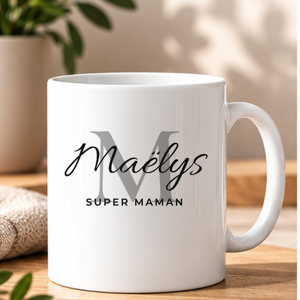 Mug blanc personnalisé Mug Prénom Signature, style Monogramme : grande initiale atténuée, prénom Maëlys en écriture Allura et petite phrase Super Maman en noir